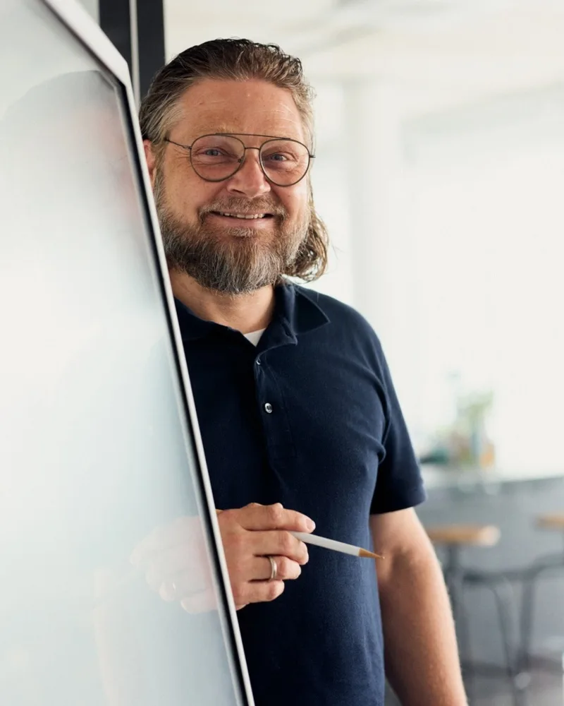 Mirco Welsing lächelt neben einem digitalen Board und hält einen Stift in der Hand