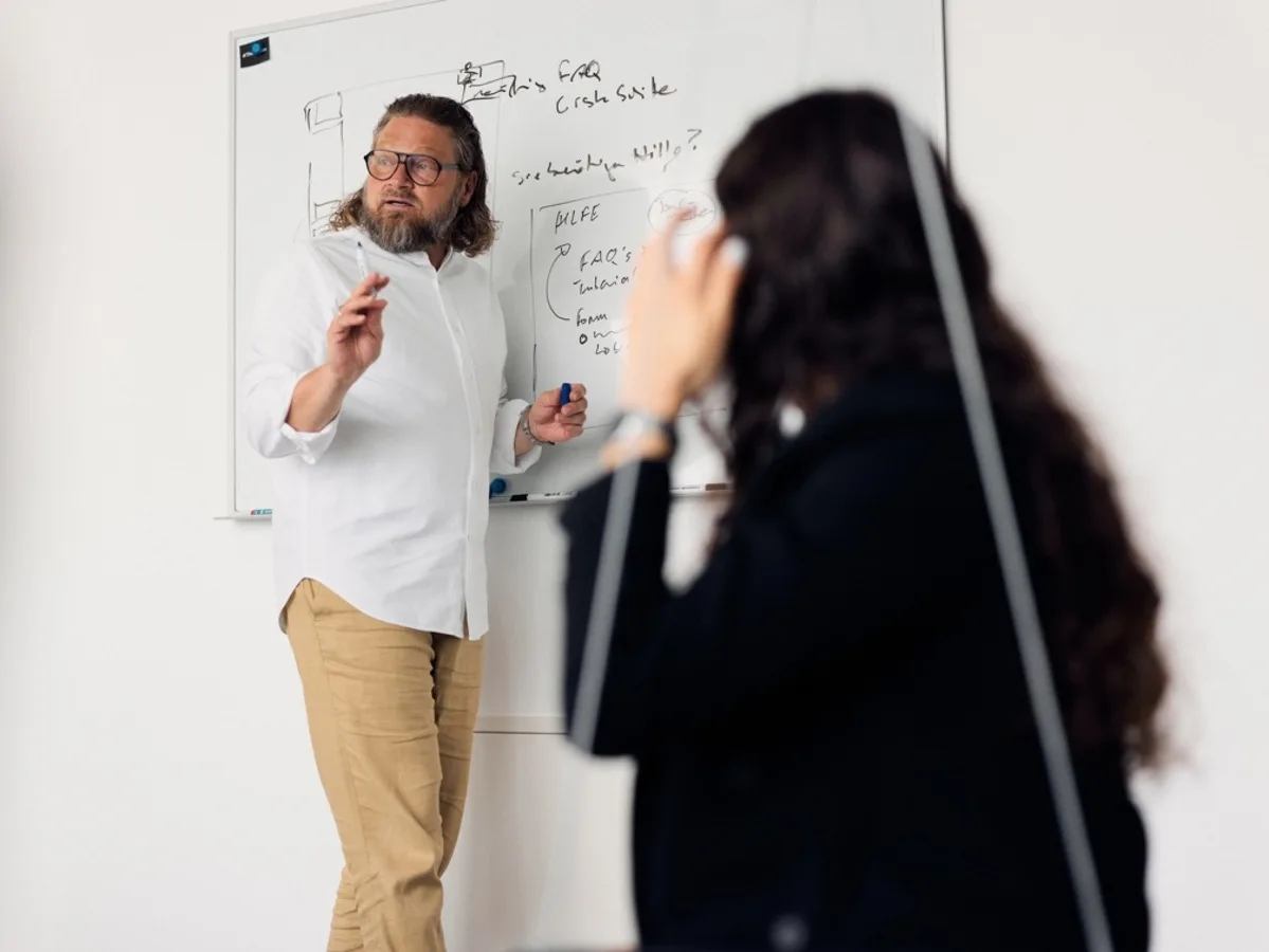Mirco Welsing erläutert während eines Workshops Zusammenhänge an einem Whiteboard